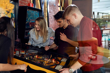 Man playing pinball watched by friends