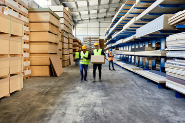 Workers moving and carrying boxes in factory warehouse