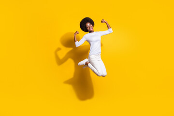 Fototapeta na wymiar Full body photo of strong happy afro american woman show muscles jump isolated on yellow color background