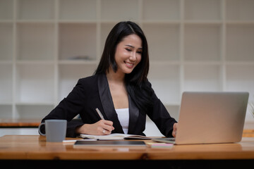 Asian business woman working on laptop computer during taking notes at the office. online meeting webinar concept.