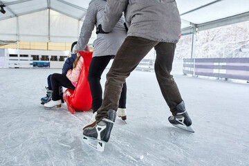 Parents pushing their children, sitting on a seal sledge, on the ice