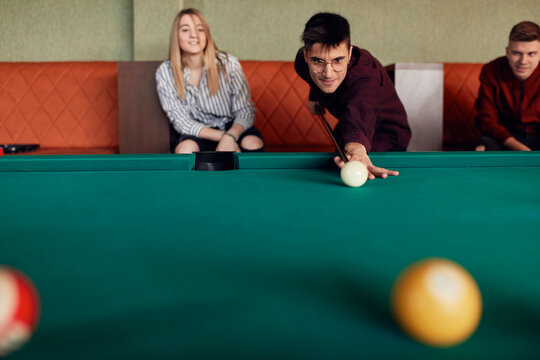 Man playing billiards watched by friends