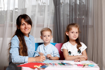 A mother with a child sits at the table and does homework. The child learns at home. Home schooling.