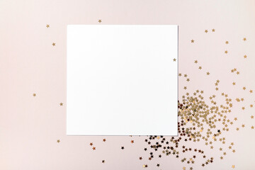 Christmas composition. Blank square paper mockup, golden stars confetti jewelry on beige background