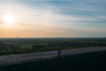Male professional standing on footpath against sky during sunset