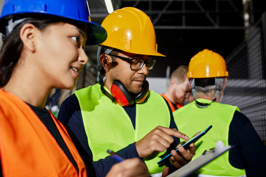 Male and female worker with clipboard and tablet talking in factory