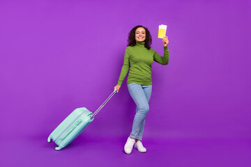 Photo of pretty charming afro woman wear green turtleneck holding tickets luggage smiling isolated purple color background