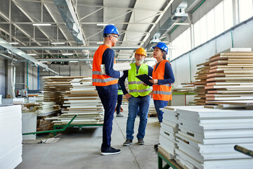 Colleagues in protective workwear talking in factory
