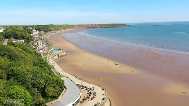 Aerial footage of the beach front in the town of Filey in the UK showing people relaxing and having fun on the sandy beach on a sunny summers day