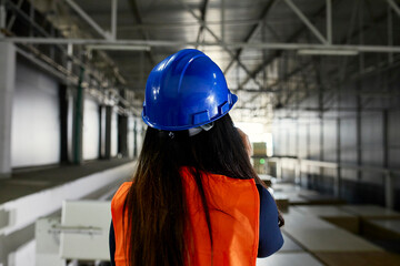 Rear view of female worker on the phone in factory warehouse
