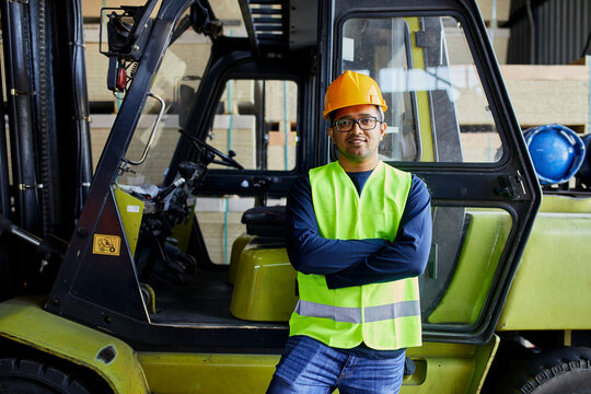 Portrait of confident worker at forklift in factory