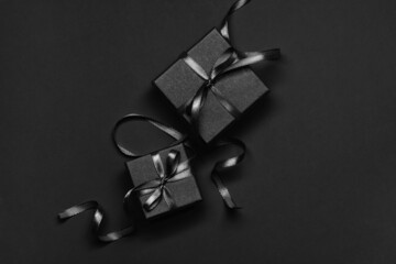 Black gift boxes tied with black ribbons on a black  background.