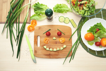A human face laid out of vegetables on a cutting board. Children's preparation of Italian salad. Flat lay.