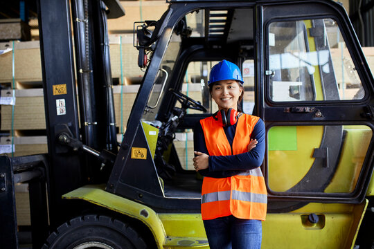 Portrait of confident female worker at forklift in factory
