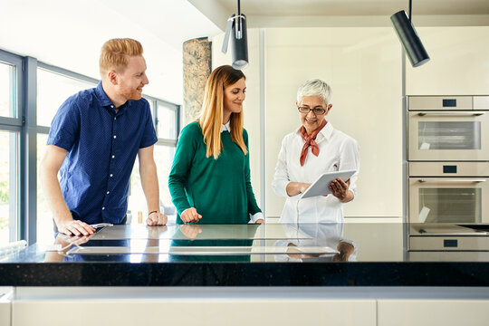Shop assistant with tablet talking to couple shopping for a new kitchen in showroom