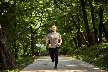 Sporty man running on forest path
