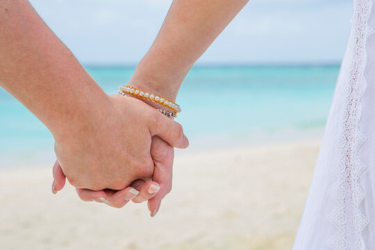 Couple holding hands at the beach, close up