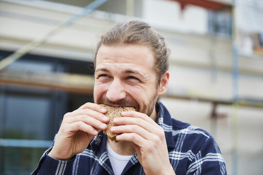 Portrait of worker having lunch break on a construction site eating a bread