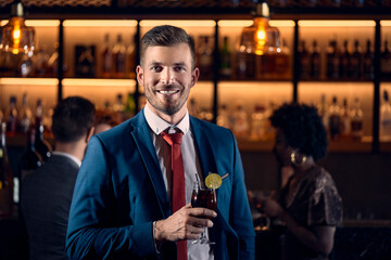 Portrait of a happy young man having a cocktail in a bar