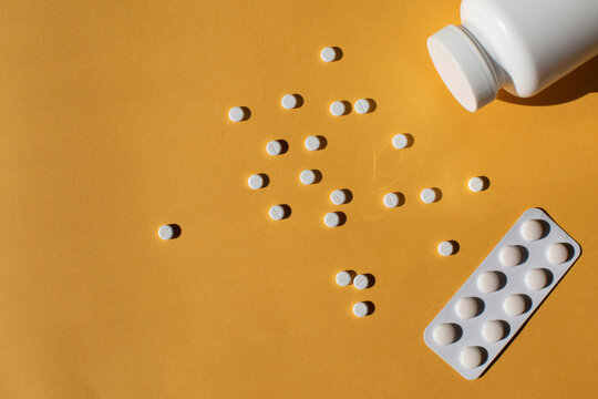 Scattered white pills against a yellow background