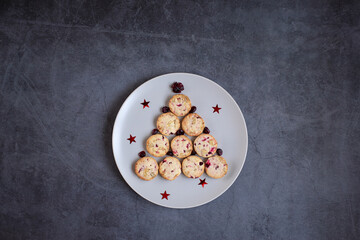 Cute edible Christmas tree made of cookies on a round plate on a grey dark background. Creative tree. Space for design and text. Concept holidays, pastries, New Year
