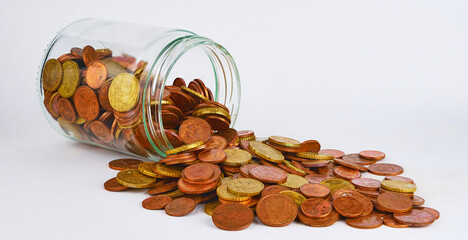euro coins in a glass jar against a white background