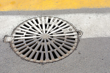 sewer hatch at a pedestrian crossing. close-up.