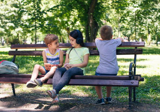 Girl wearing headphones talking to friend in park