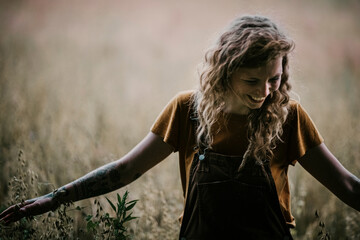 Smiling woman touching crop while standing in agricultural field