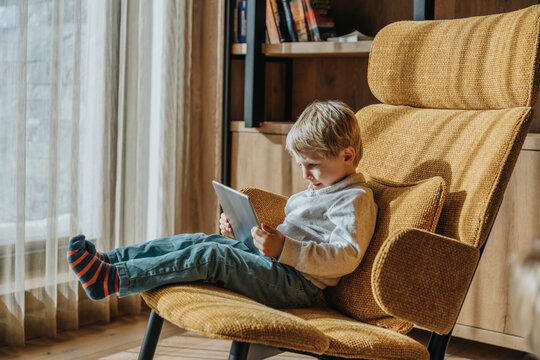 Boy e-learning while sitting on chair in living room