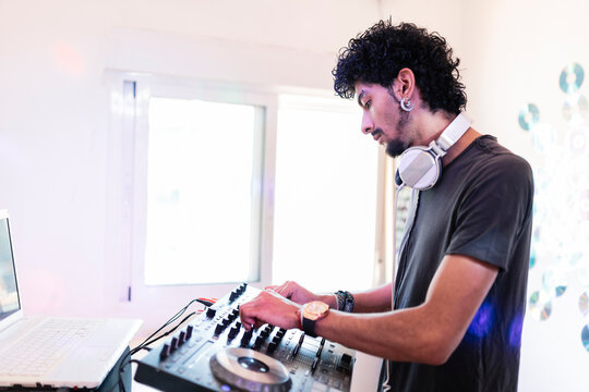 Young male musician mixing sound while DJing at recording studio