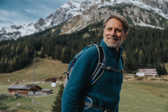 Smiling mature man with backpack looking away while standing at Hochkonig, Salzburger Land, Austria
