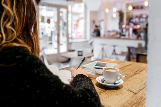 Woman writing in notebook in coffee shop