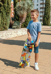 Preschooler boy in t-shirt stays with a skateboard in a park. Shirt mockup © katrinshine