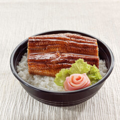 Cooked steamed rice topped with grilled eel or Unagi don Japanese food isolated on white cloth background..