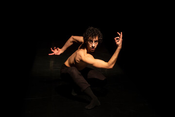Male ballet dancer performing on black stage