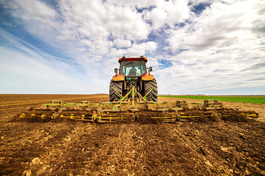 Back view of farmer in tractor plowing field in spring