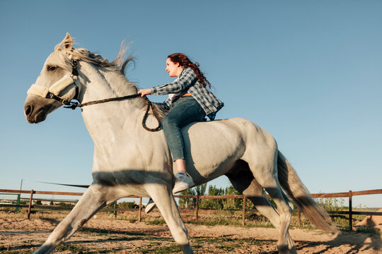 Woman horseback riding at equestrian center against clear sky