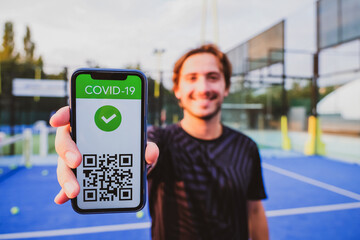 Young man showing vaccination certificate covid-19 with app on smartphone first to do sport,...
