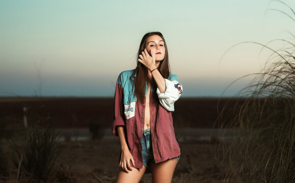 Portrait of beautiful young woman standing against sky during sunset
