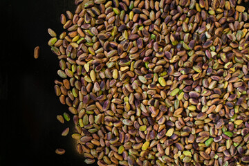 Baked pistachio on a black baking sheet.