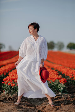 Portrait of fashionable woman dressed in white standing in front of tulip field