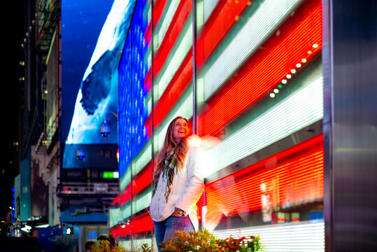 USA, New York, New York City, Portrait of young beautiful woman leaning on Times Square LED display at night
