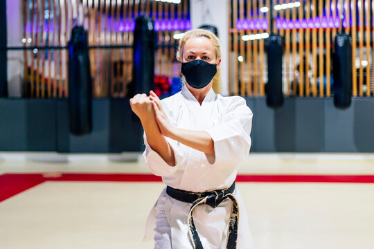 Mature woman wearing face mask practicing karate in health club