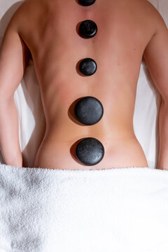 Young woman lying on massage table during lastone therapy at health spa