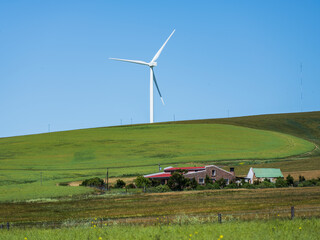 Fototapeta premium Close up shot of countryside house and a wind turbines with blue sky in the overberg Western Cape South Africa