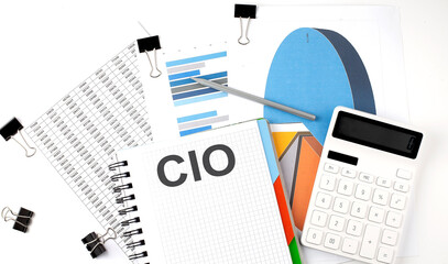 Text CIO on a notebook on the diagram and charts with calculator and pen