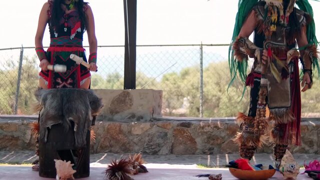 Pre-Hispanic dancers playing instruments with bright sky as background