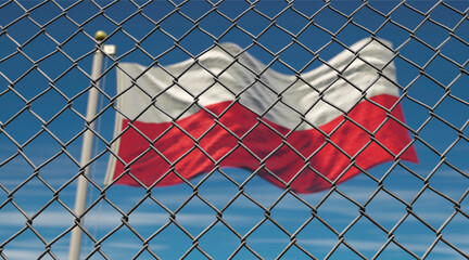 Maschendrahtzaun mit polnischer Flagge im Hintergrund