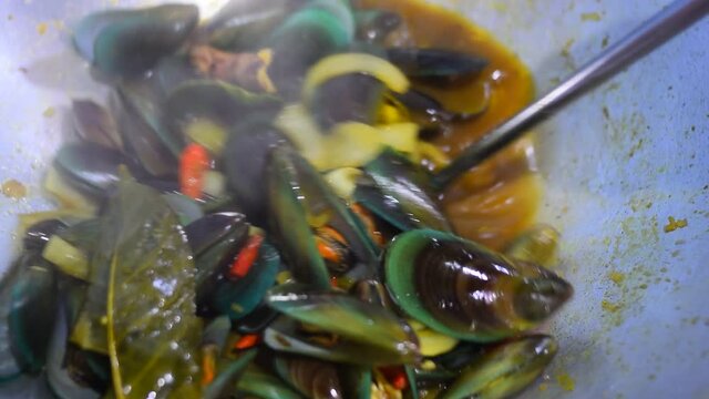 Cooking spicy and delicious green mussels in a cooking pot